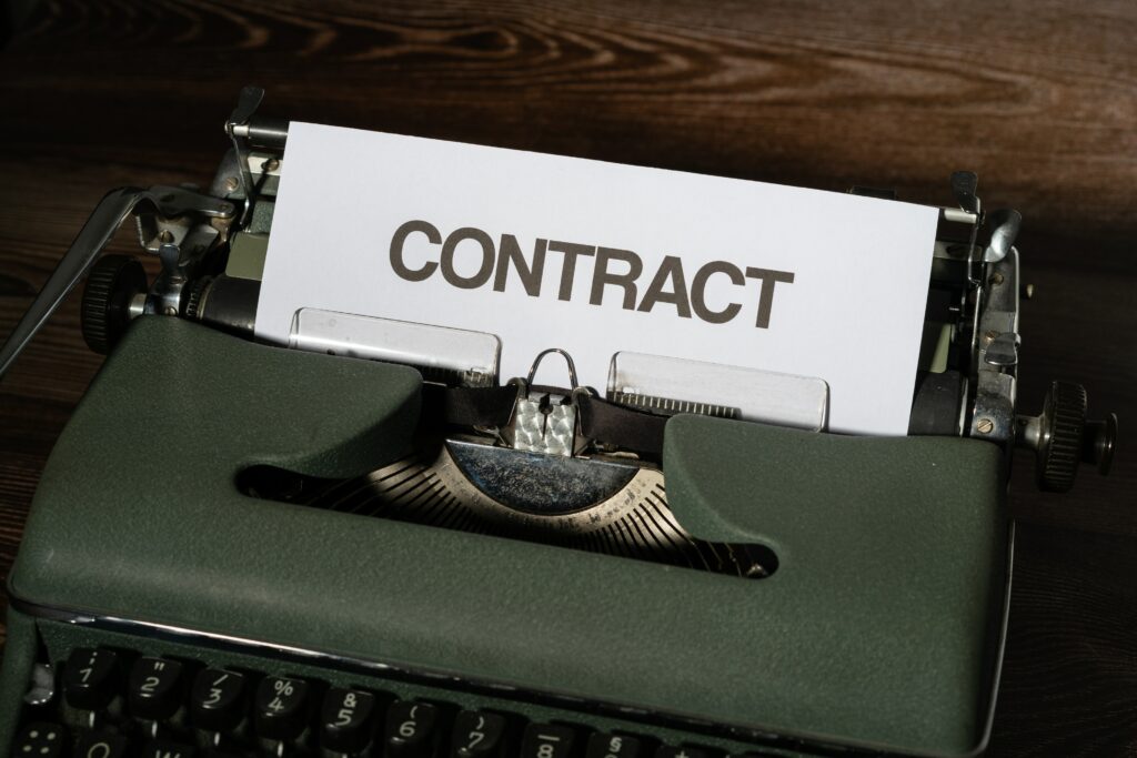 A paper entitled 'Contract' ready to be annotated in a manual typewriter.